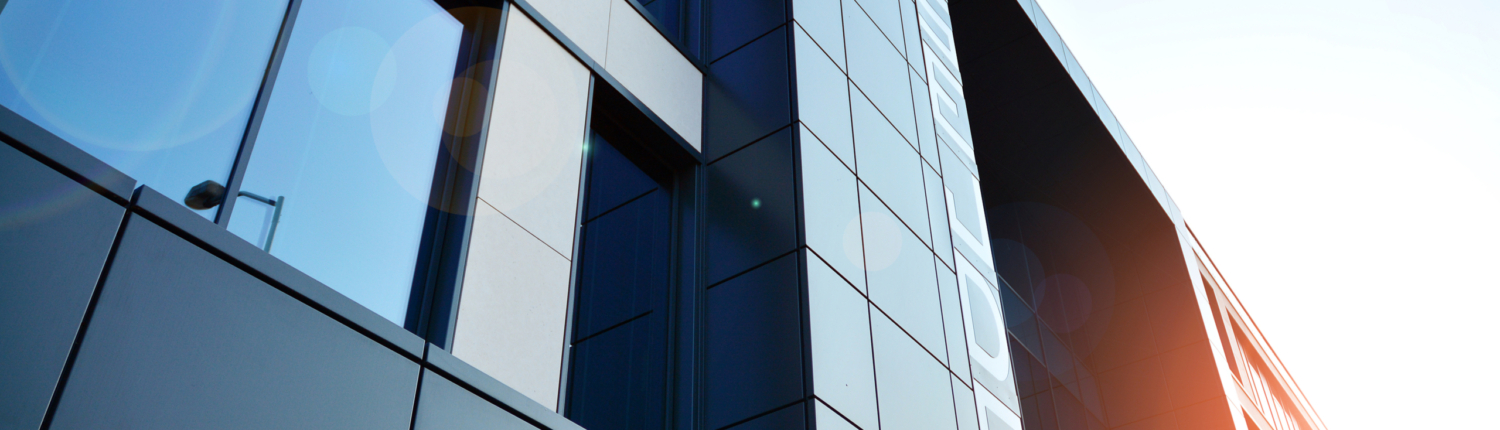 Futuristic facade of a modern office building clad in glass. Glass cladding panels and windows of modern building. An office building with geometry and perspective.